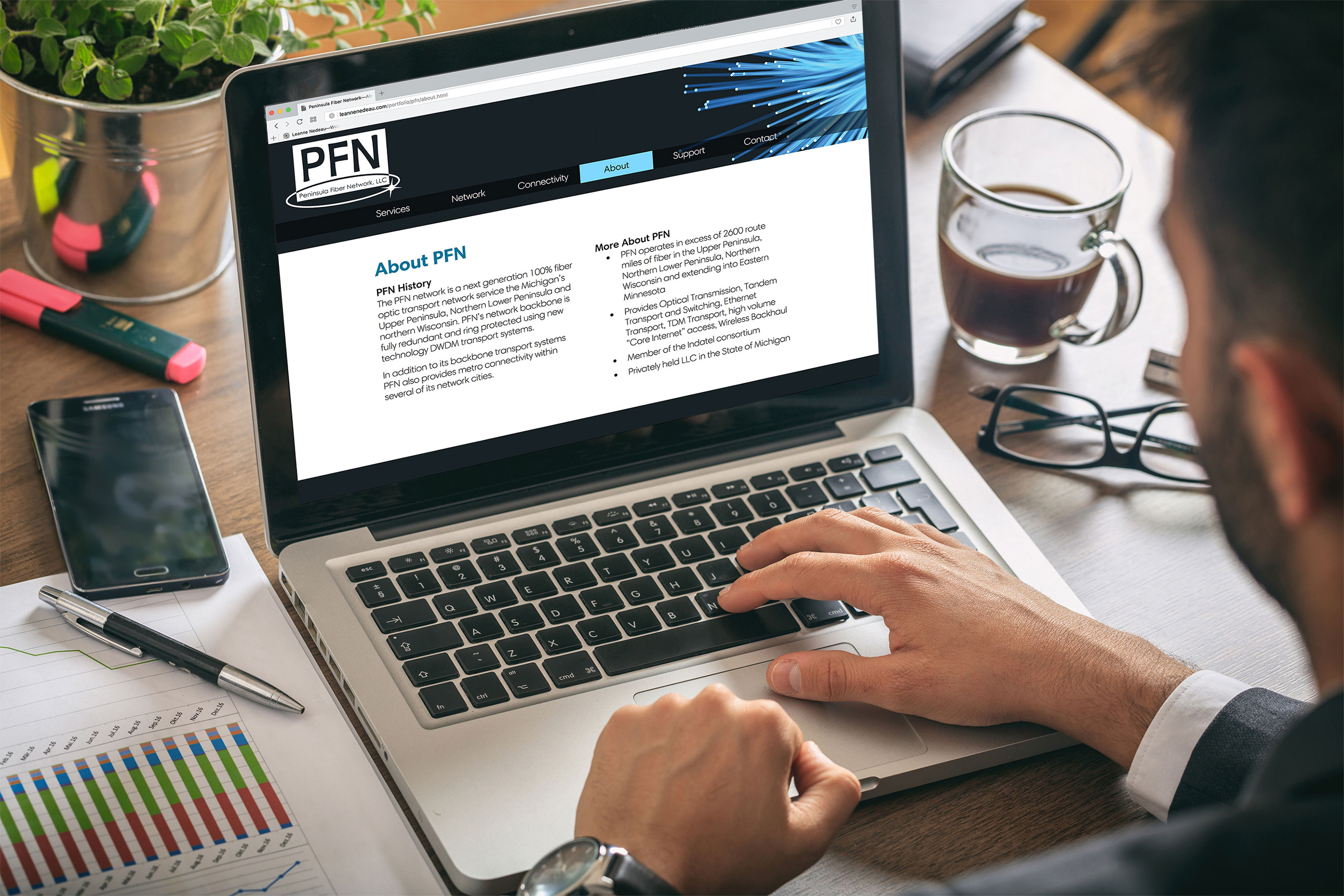 A photograph taken over the sholder of a middle-aged man in business attire at his desk at work with his laptop open with the PFN website loaded on the screen.