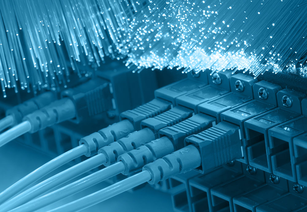 Fiber jumpers plugged into a switch, with decorative raw fiber optic wires draped above the switch and fiber jumpers.